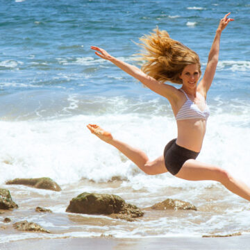 Carisa Carroll performing a graceful leap on the beach in Santa Barbara, CA, captured by Coldea Productions.
