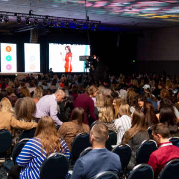 Event-Photography Event photography at the Los Angeles Convention Center featuring a keynote speaker engaging with a large audience, visually documented by Coldea Productions to highlight the professional atmosphere and immersive experience