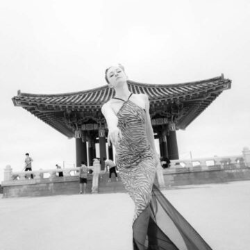 Fashion model in an elegant dress posing gracefully in front of the Korean Friendship Bell, showcasing Coldea Productions' expertise in fashion and dance photography