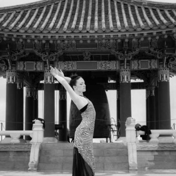 Elegant dancer in a flowing dress poses gracefully in front of the Korean Friendship Bell, highlighting Coldea Productions' expertise in fashion and dance photography.