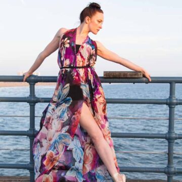 Dancer posing in a floral dress on a pier with the ocean in the background, showcasing fashion and dance photography by Coldea Productions.