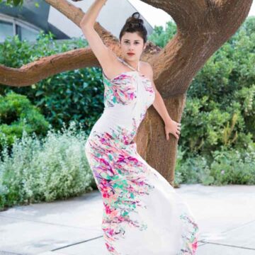 Woman in a vibrant floral dress posing gracefully by a tree, showcasing fashion, dance, and portrait photography by Coldea Productions.
