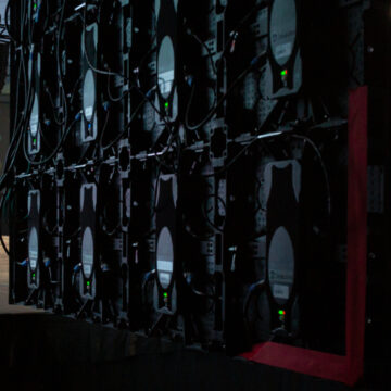 Convention-Photography Side view of a conference stage with presenters and LED screens, showcasing event production details and live audience engagement.
