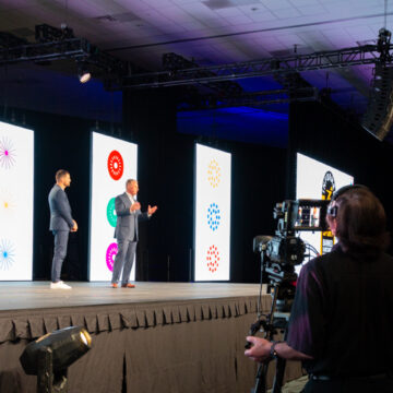 Convention-Photography Camera operator filming speakers on stage at the Scentsy conference, highlighting Coldea Productions' expertise in event video production.