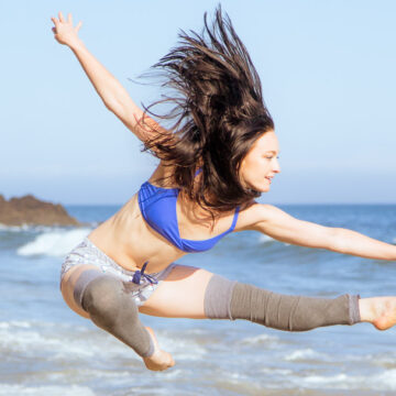 Dancer Nikiya Palombi performing an athletic leap on the beach in Santa Barbara, CA, captured by Coldea Productions.