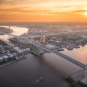 Aerial view of a cityscape at sunset, with an intricate bridge spanning a river, captured by Coldea Productions' drone photography services