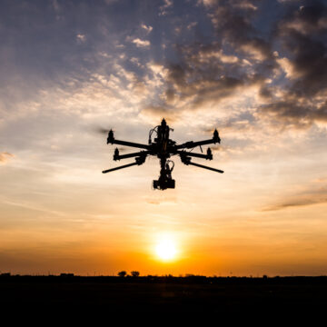 Silhouette of a drone capturing aerial footage at sunset, showcasing Coldea Productions’ drone and aerial video services