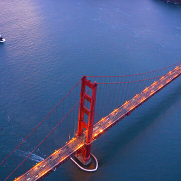 Aerial view of the Golden Gate Bridge at dusk with a ship passing nearby, showcasing Coldea Productions' aerial photography services.