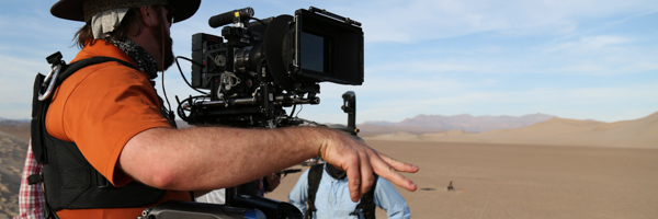 A videographer operating professional camera equipment in a desert landscape, showcasing Coldea Productions’ expertise in aerial drone videography