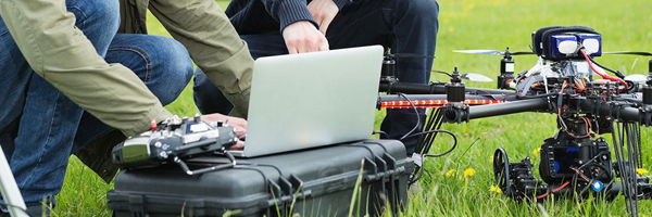 Technicians preparing a drone and operating a laptop in a field, representing Coldea Productions' expertise in aerial videography.