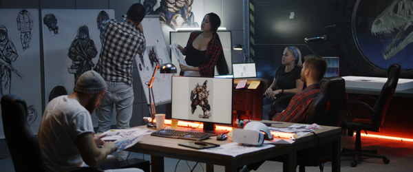 A team of designers and animators at work, sketching and creating character designs in a studio with monitors, sketches, and digital drawing equipment.