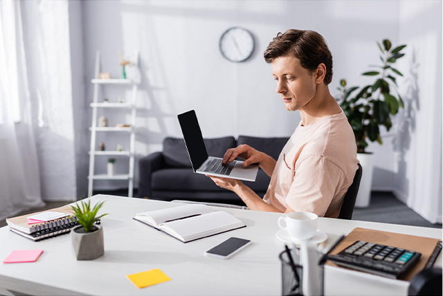 Young professional working on a laptop at a desk in a modern home office setting.