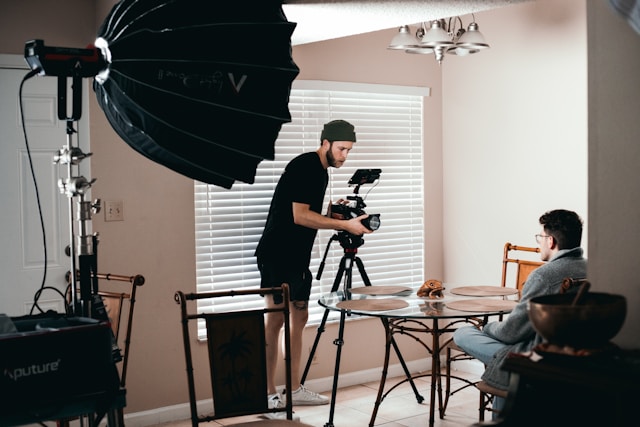 Videographer recording an interview with lighting equipment in a home studio setting for visual storytelling production.