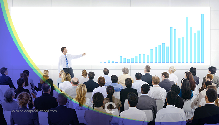 A business professional presenting a bar graph to an audience, representing Coldea Productions' expertise in creating effective training videos.