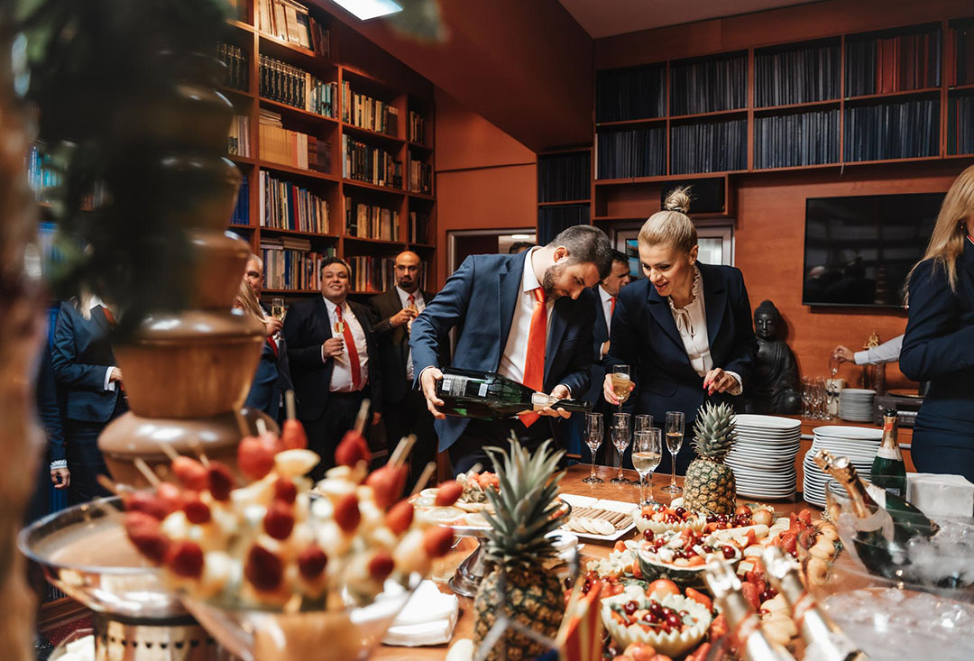 A formal corporate awards event with a vibrant buffet table, featuring attendees in suits enjoying drinks and conversations