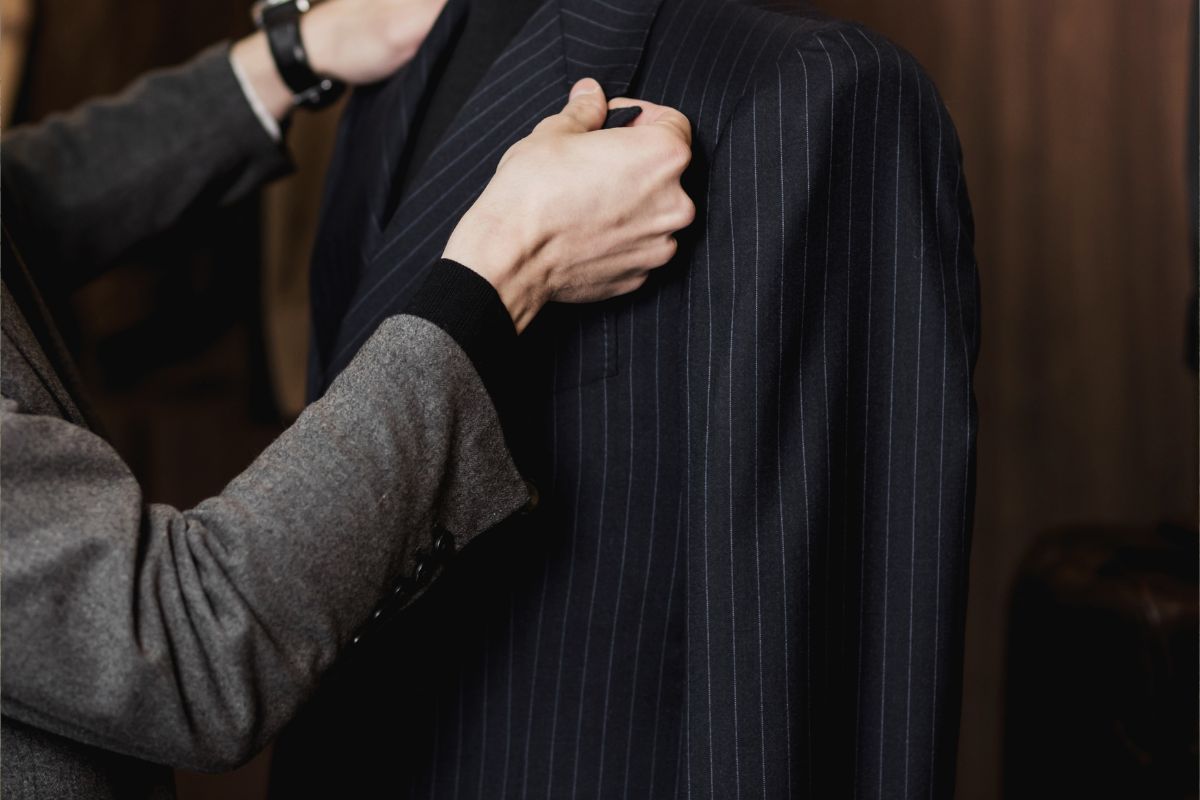 Tailor adjusting a custom suit jacket, symbolizing the precision and craftsmanship in custom clothing.
