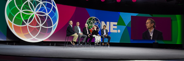 Panel of speakers on stage with colorful backdrop and screen projection, ideal for corporate events at Shrine Auditorium, captured by Coldea Productions.