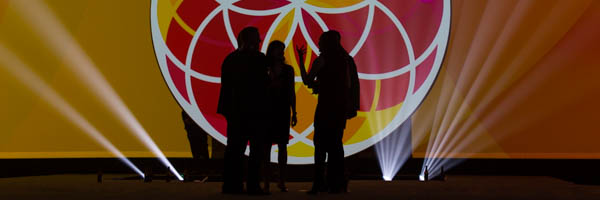 Silhouetted speakers with dramatic lighting and vibrant backdrop, ideal for event photography in Riverside, California, by Coldea Productions.