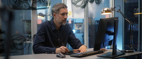 Professional video editor working on a computer in a creative studio setting, designing promotional content.