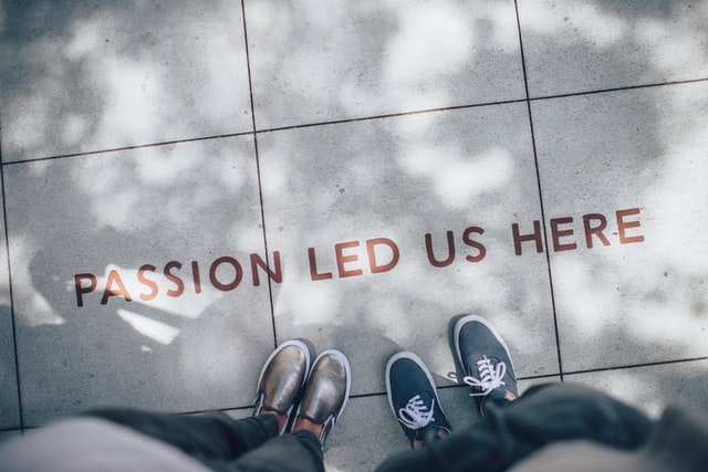 Two individuals standing near a sidewalk inscription reading "Passion Led Us Here," symbolizing the drive behind brand collaborations, captured by Coldea Productions
