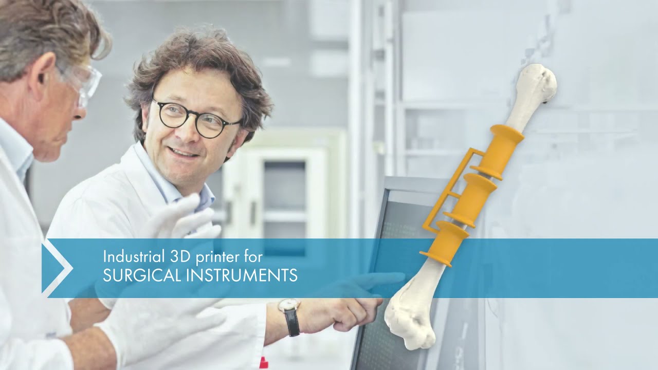 Researchers discussing the use of an industrial 3D printer for surgical instruments, with a bone model being printed on the screen.