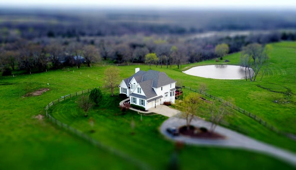 A white house with a grey roof near a small lake.