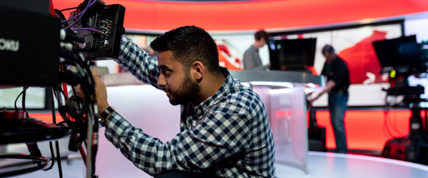 Videographer adjusting camera equipment in a modern broadcast studio for live streaming production