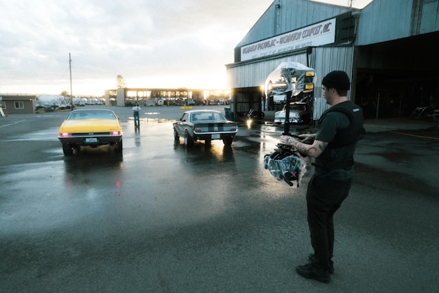 Cinematographer filming classic cars at an industrial location during a Coldea Productions automotive video shoot at sunset.