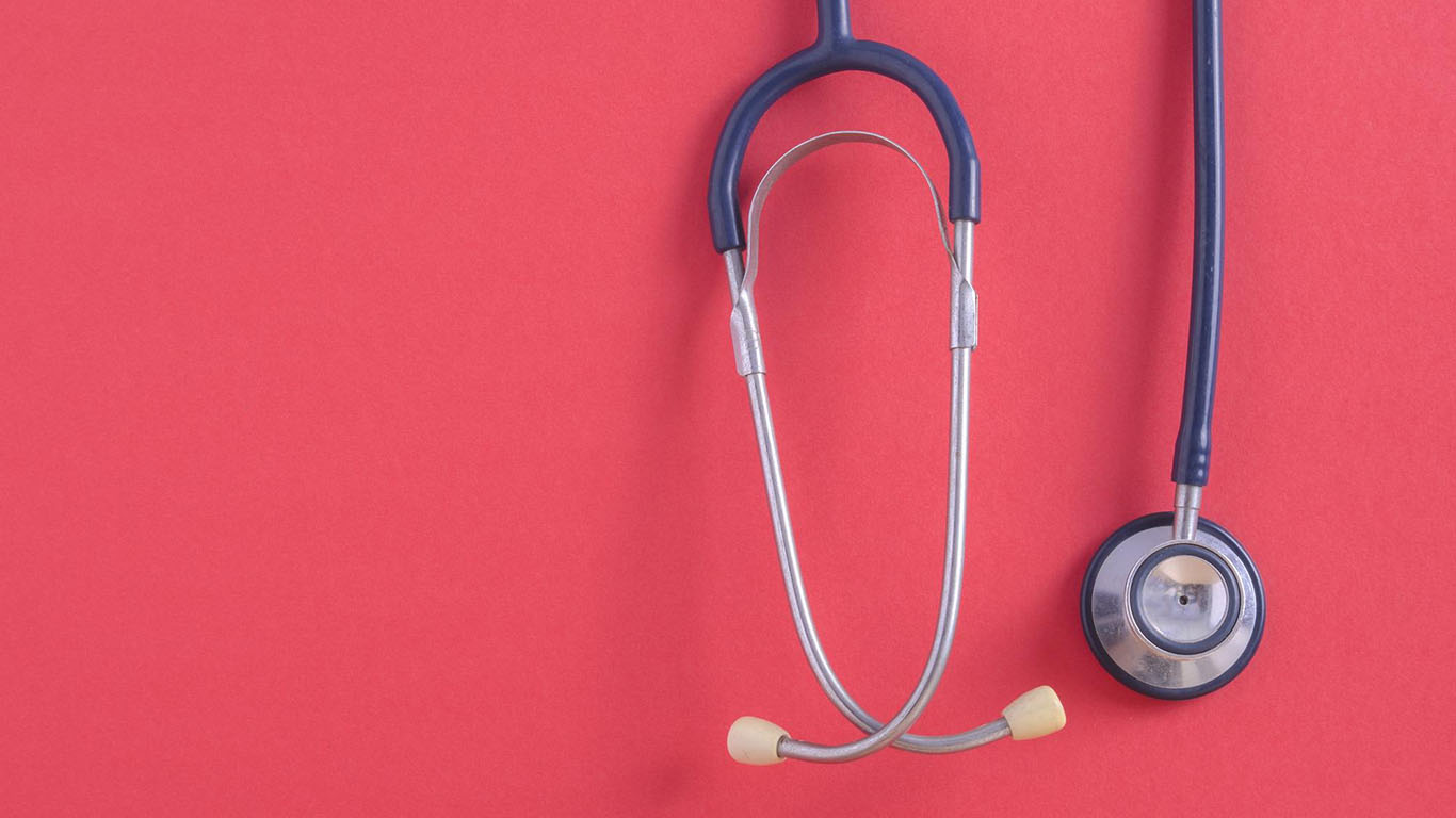 A stethoscope placed on a vibrant red background, symbolizing healthcare and medical services.