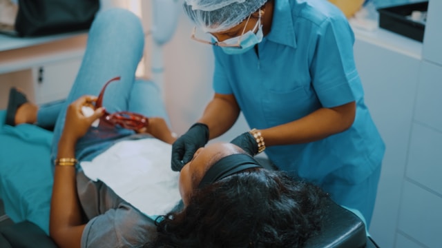 Orthodontist in blue scrubs treating a patient during a dental procedure, showing authentic patient care for NYC orthodontic case studies.