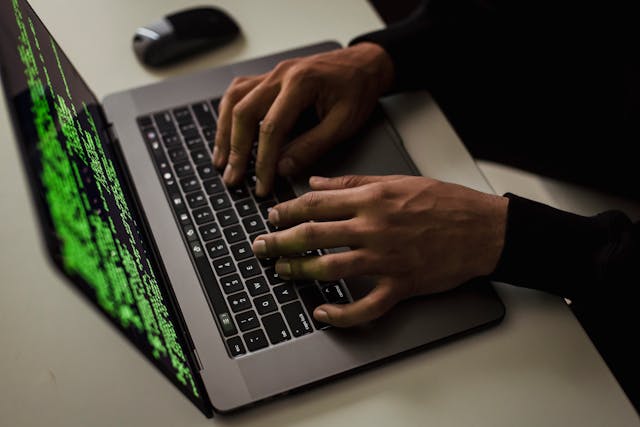 Hands typing code on a laptop during a cybersecurity phishing defense test.