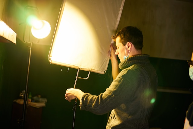 Professional lighting technician adjusting a softbox in a studio, illustrating how control of light and shadow shapes the mood and tone in photography by Coldea Productions.