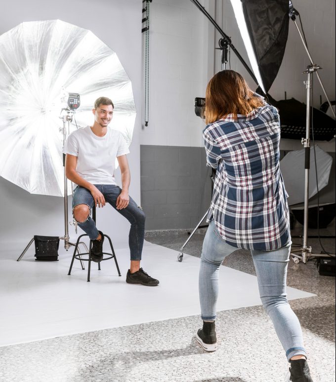 Photographer taking a picture of a male model in a studio with professional lighting equipment.
