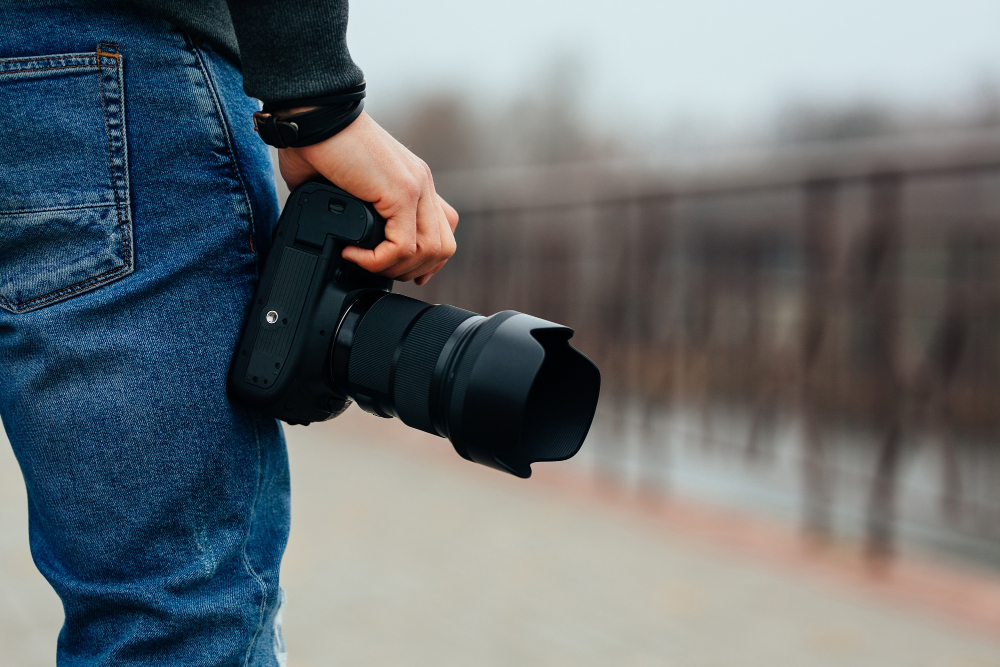 Close-up of a photographer holding a professional camera, ready for an outdoor photo shoot, showcasing Coldea Productions’ expertise in capturing high-quality images.