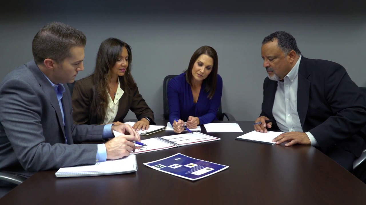 A group of professionals sitting around a conference table, reviewing documents and discussing a project, symbolizing collaboration and strategic planning.