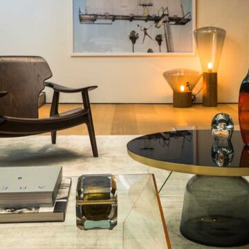 A stylish living room interior with a modern chair, glass coffee table, and artistic decor, showcasing real estate photography by Coldea Productions.