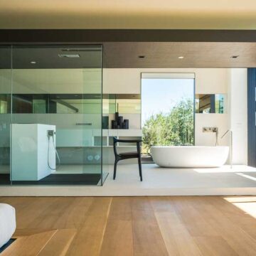 A luxurious, modern bathroom with a glass shower enclosure, freestanding bathtub, and open layout, captured as part of Coldea Productions' real estate photography services.