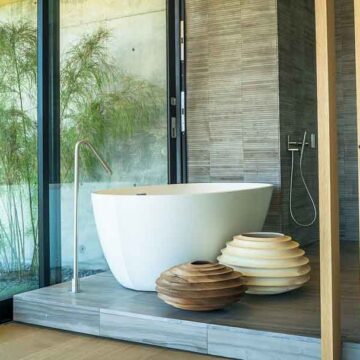 Modern bathroom with a freestanding tub, large windows, and natural decor, showcasing real estate photography by Coldea Productions.