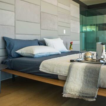 A modern, well-designed bedroom with minimalist decor and glass wall features, showcasing real estate photography by Coldea Productions.