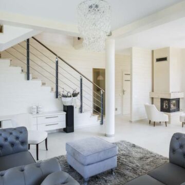 Modern, elegant living room with staircase and contemporary decor, showcasing real estate photography by Coldea Productions.
