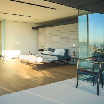 Modern, minimalist bedroom with glass walls and scenic views, captured by Coldea Productions for real estate photography.