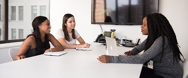 Three women engaged in a professional meeting, ideal for recruiting video production showcasing workplace diversity and collaboration.