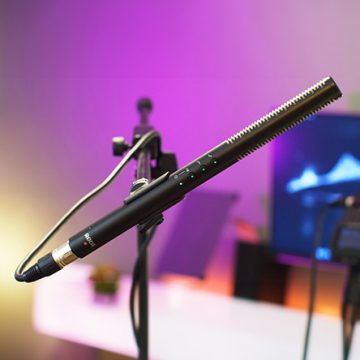 Rode NTG4+ shotgun microphone mounted on a stand with a purple and yellow-lit background.