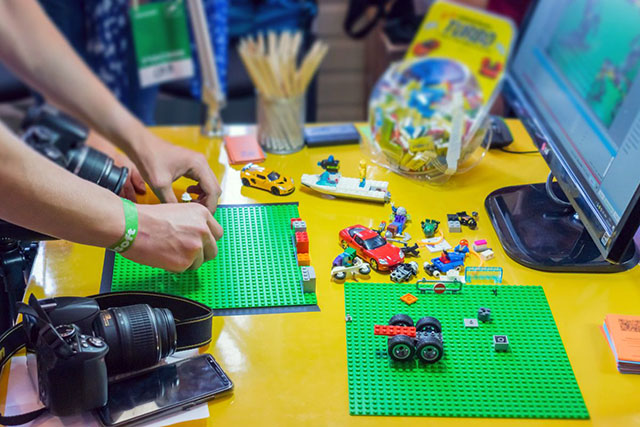 Hands setting up a stop-motion animation scene with LEGO pieces on a desk