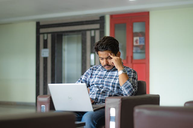 Man looking concerned while using a laptop, symbolizing phishing risks and cybersecurity challenges.