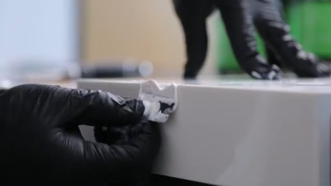A close-up of gloved hands repairing a surface, focusing on detailed work for a NEOLITH product.