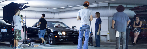 Film crew working in a parking garage with lighting equipment and a black car, part of Coldea Productions' video production services in Rancho Santa Margarita, California