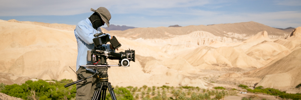 Cinematographer operating a camera on location in a desert setting, part of Coldea Productions' video production services in Riverside, California