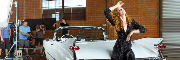 Actress posing on a classic white convertible during a video production shoot in Santa Monica, California.