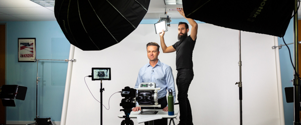 Rob Gledhill of Blue-White Industries demonstrates the functionality of Plastic Chemical Feed Skids while Alexis Mendez from Coldea Productions adjusts lighting during the video shoot.